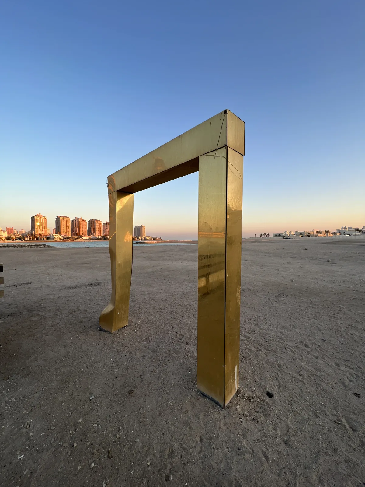 Gold rectangular frame sculpture on the West Bay Lagoon shoreline, Doha
