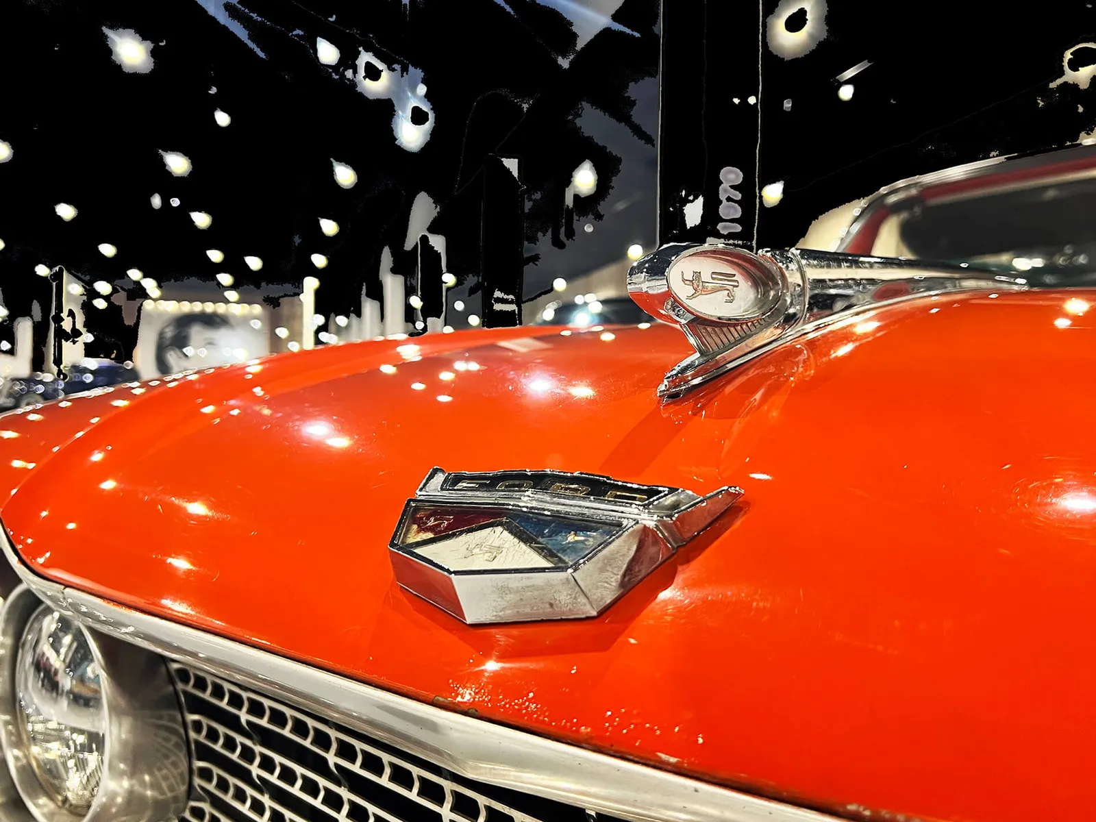 Close-up of a red vintage car's chrome grille and headlight