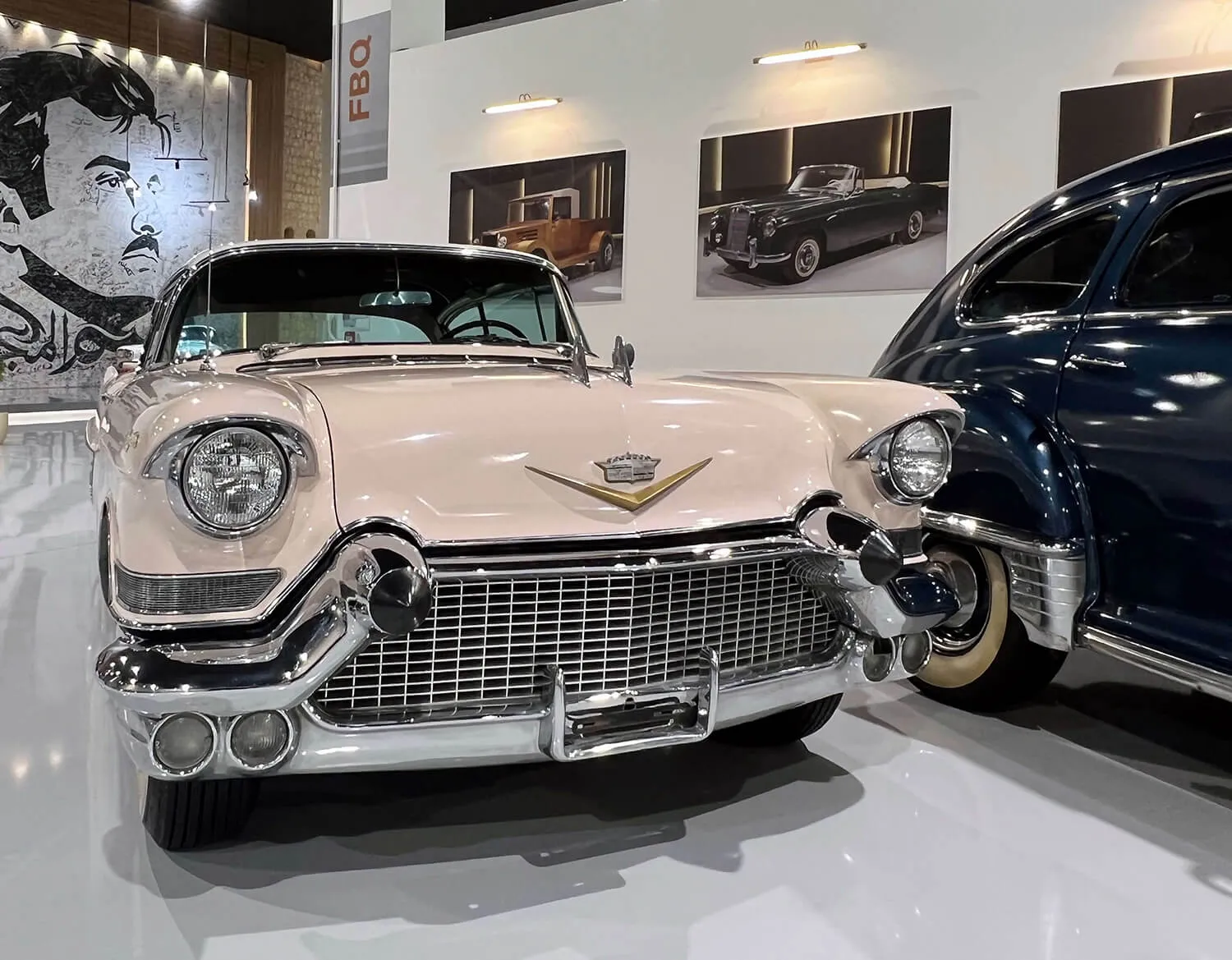 Cream classic Cadillac with chrome fins next to a black vintage car