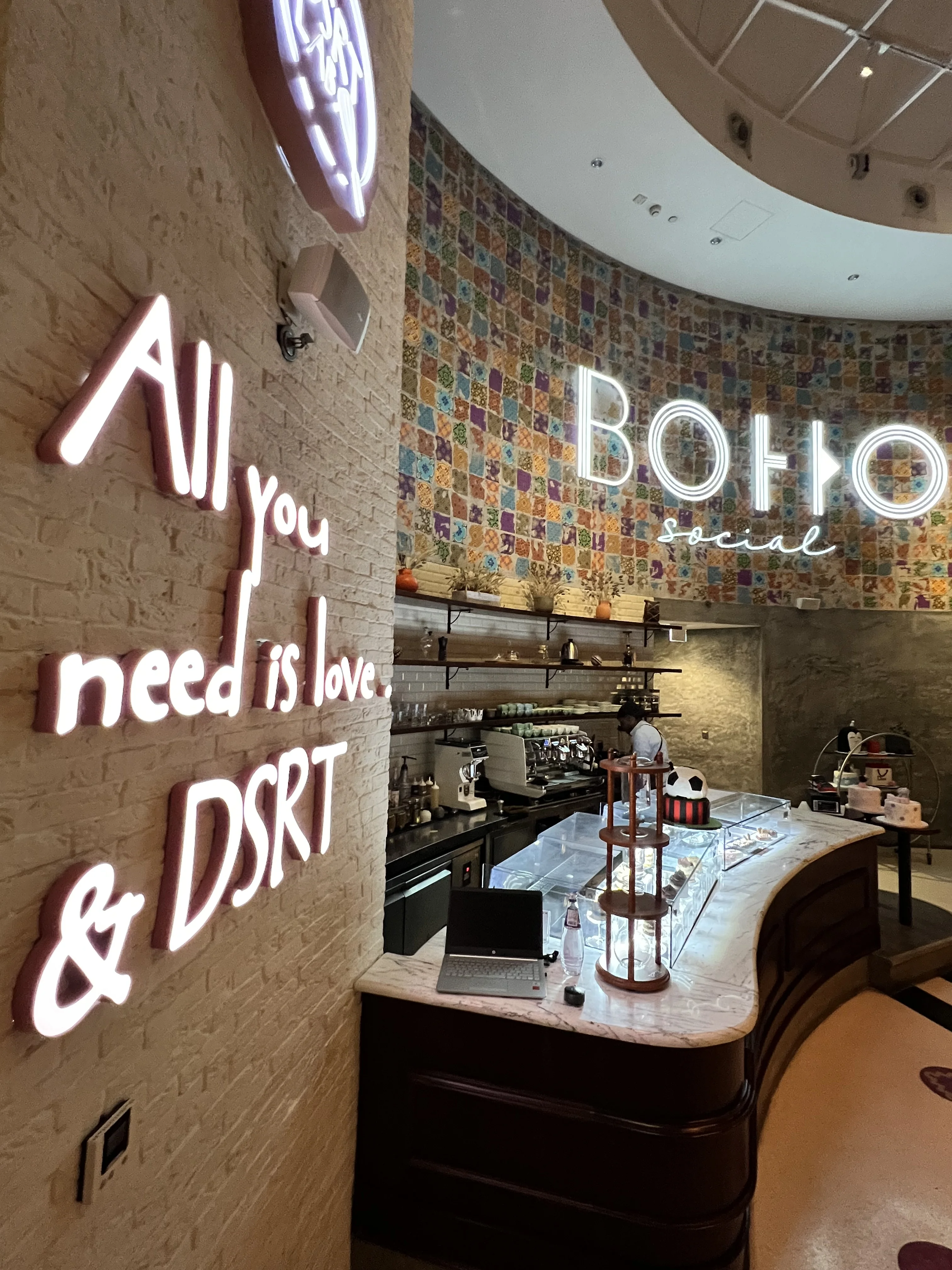 Dessert bar counter with neon signage inside Boho Social restaurant, Doha