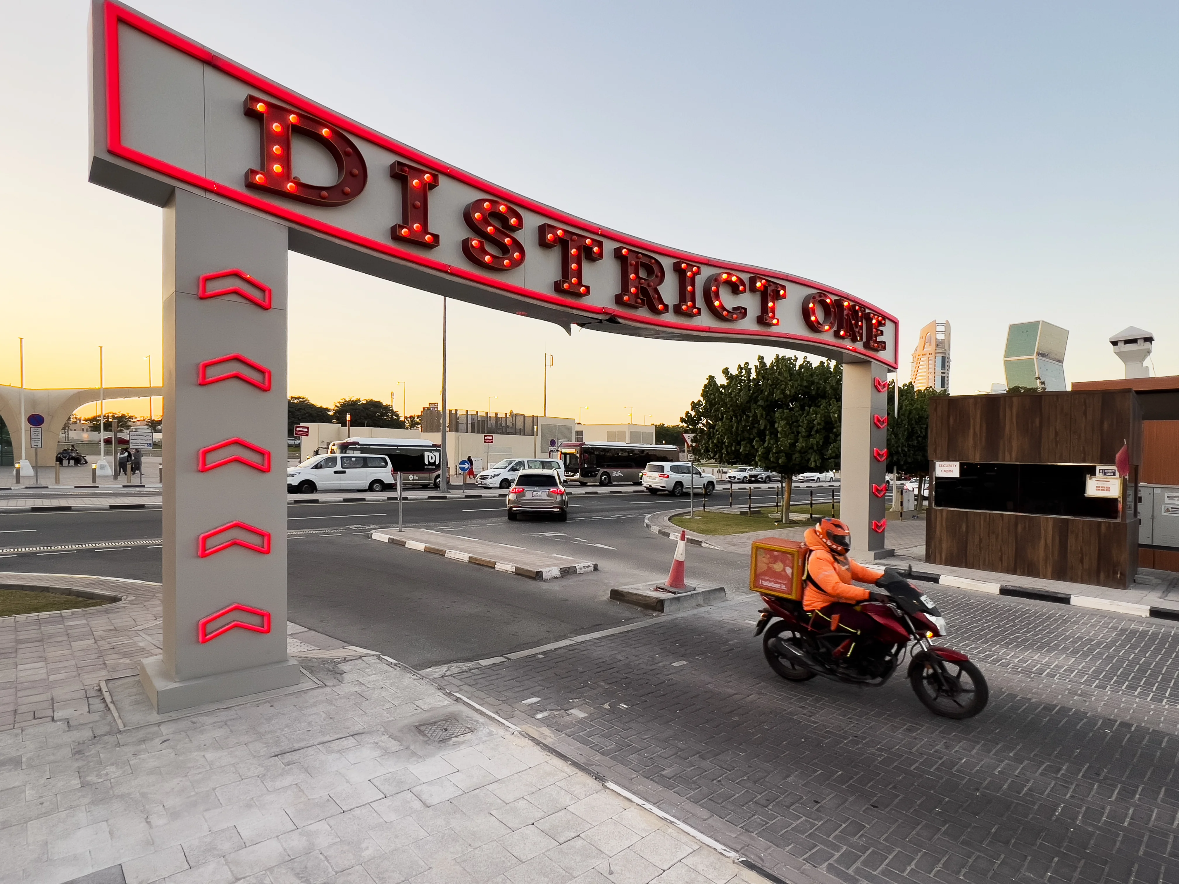 Red 'District One' entrance sign over the road at Legtaifiya, Doha, at dusk