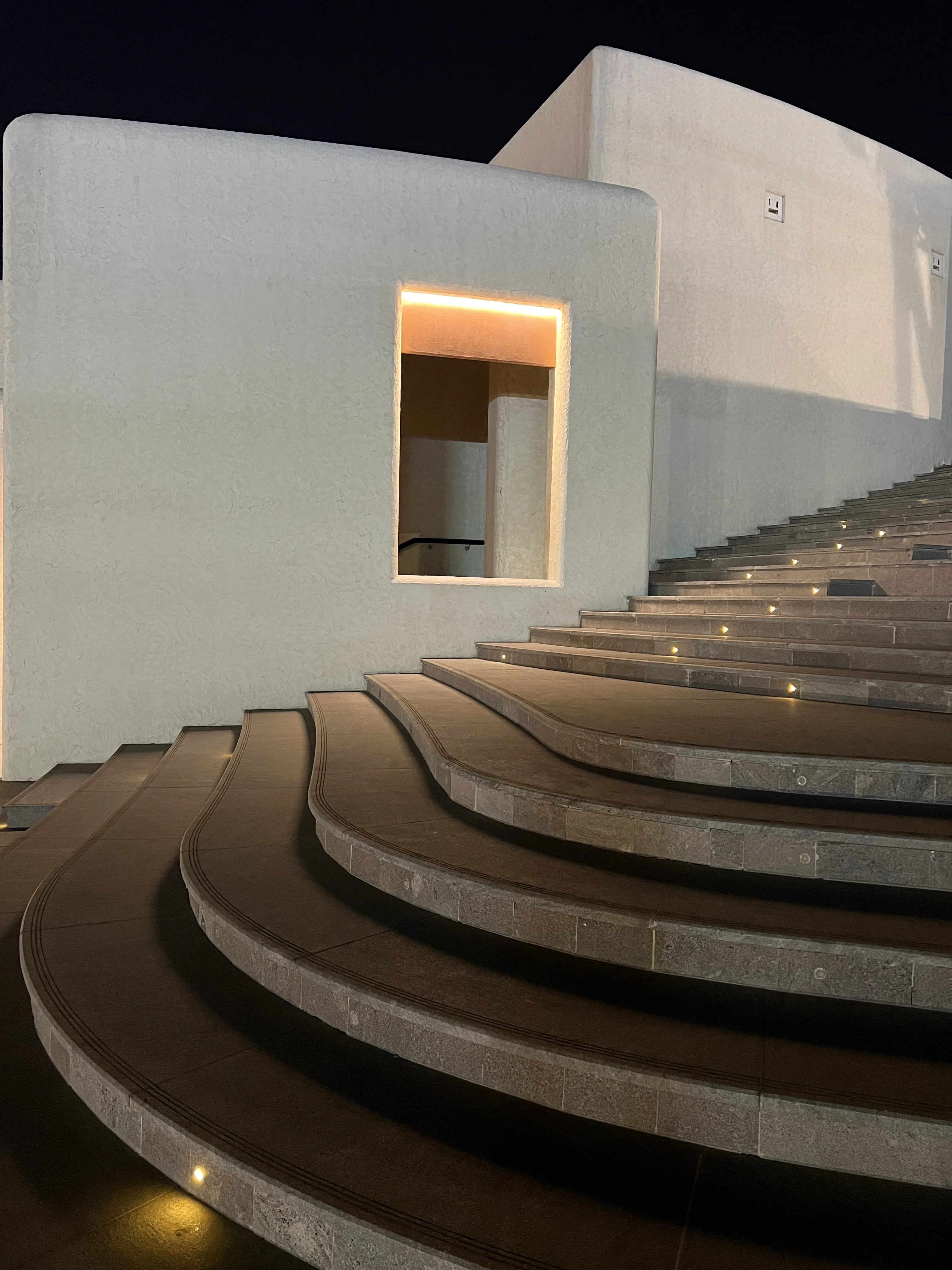 Arched limestone colonnade building beside Katara Amphitheatre lit at night