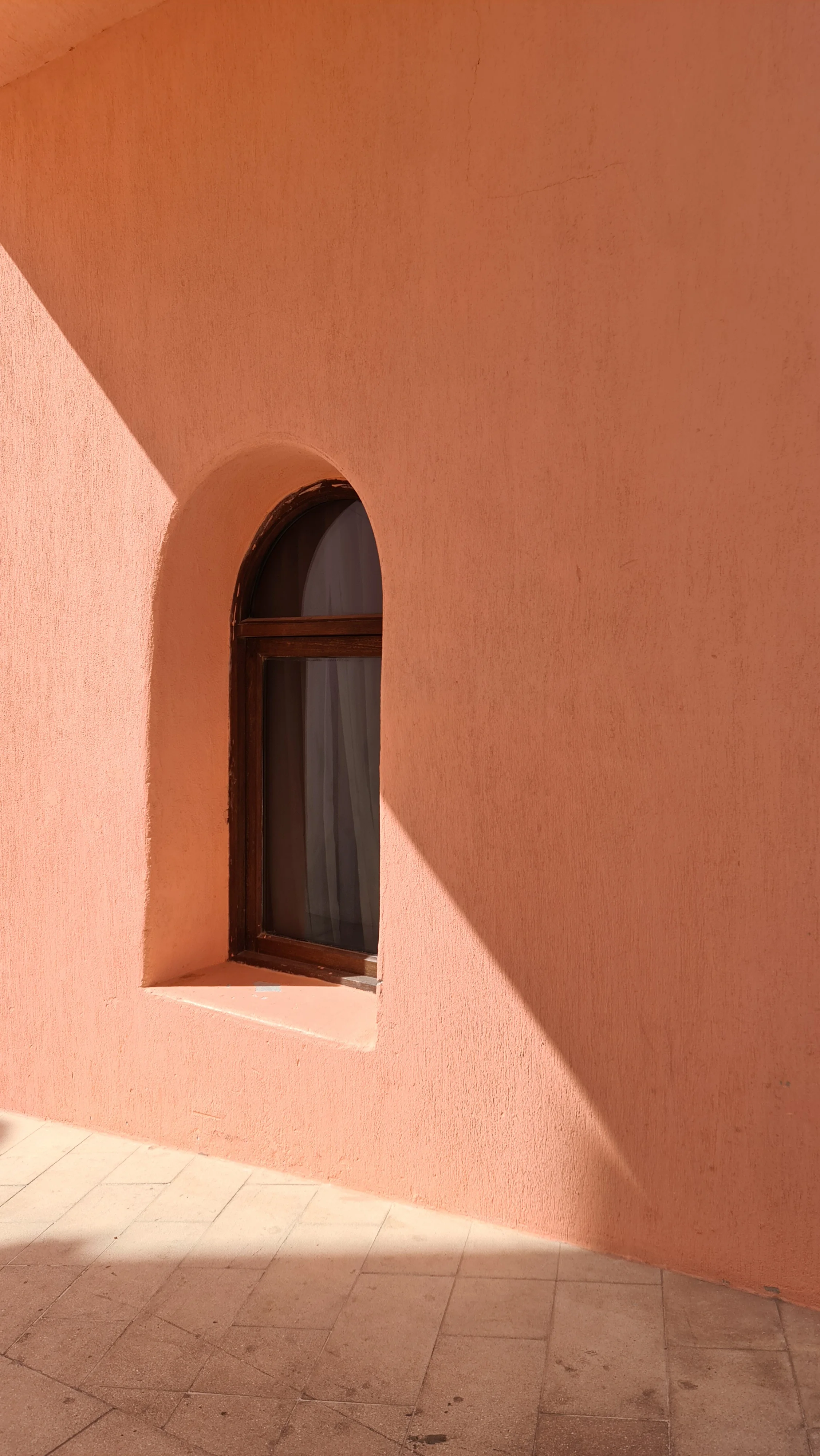 Pastel pink stucco building facade with an arched window in the Mina District, Doha