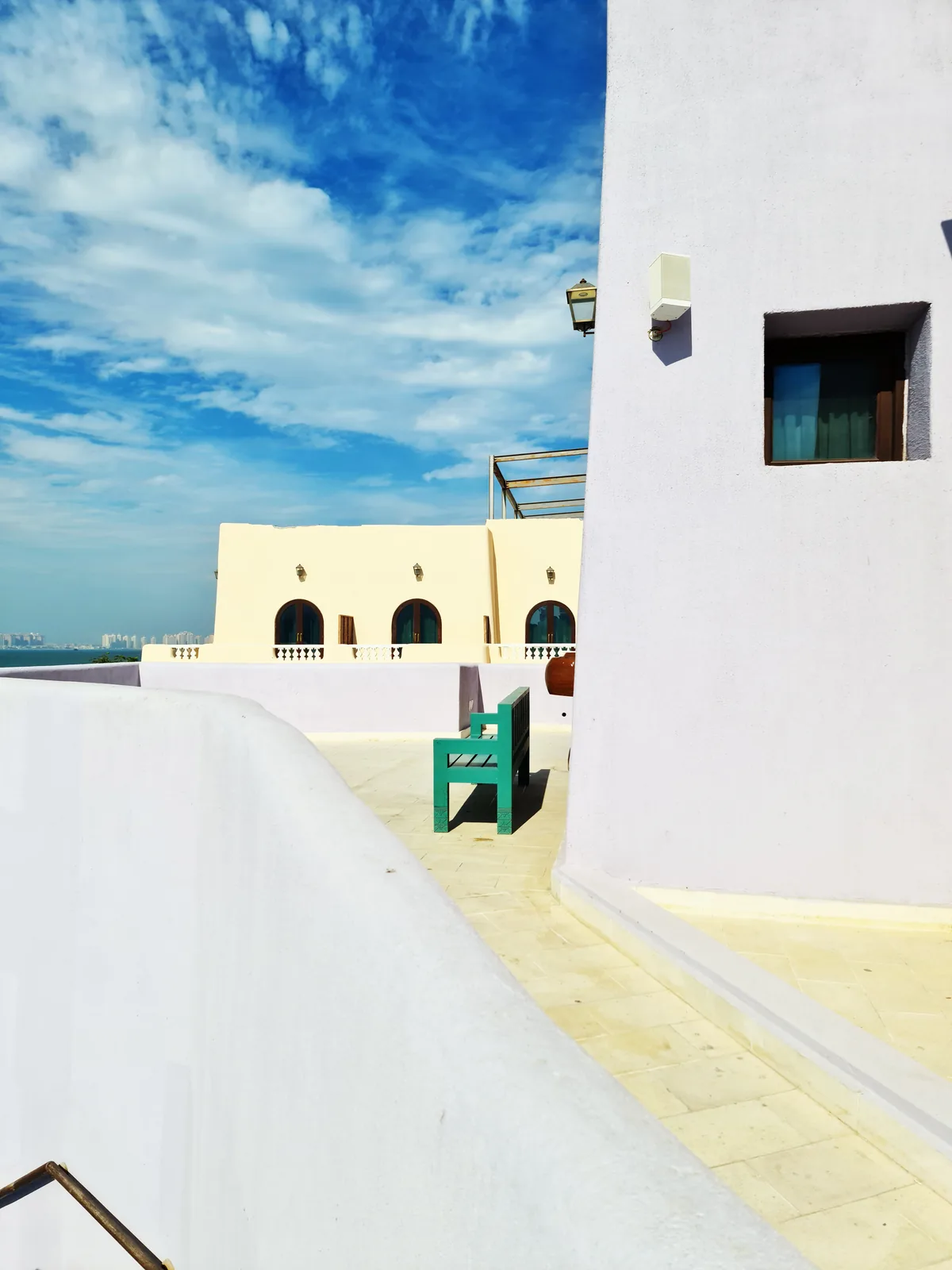 White rooftop terrace with steps and pastel walls in the Mina District, Doha
