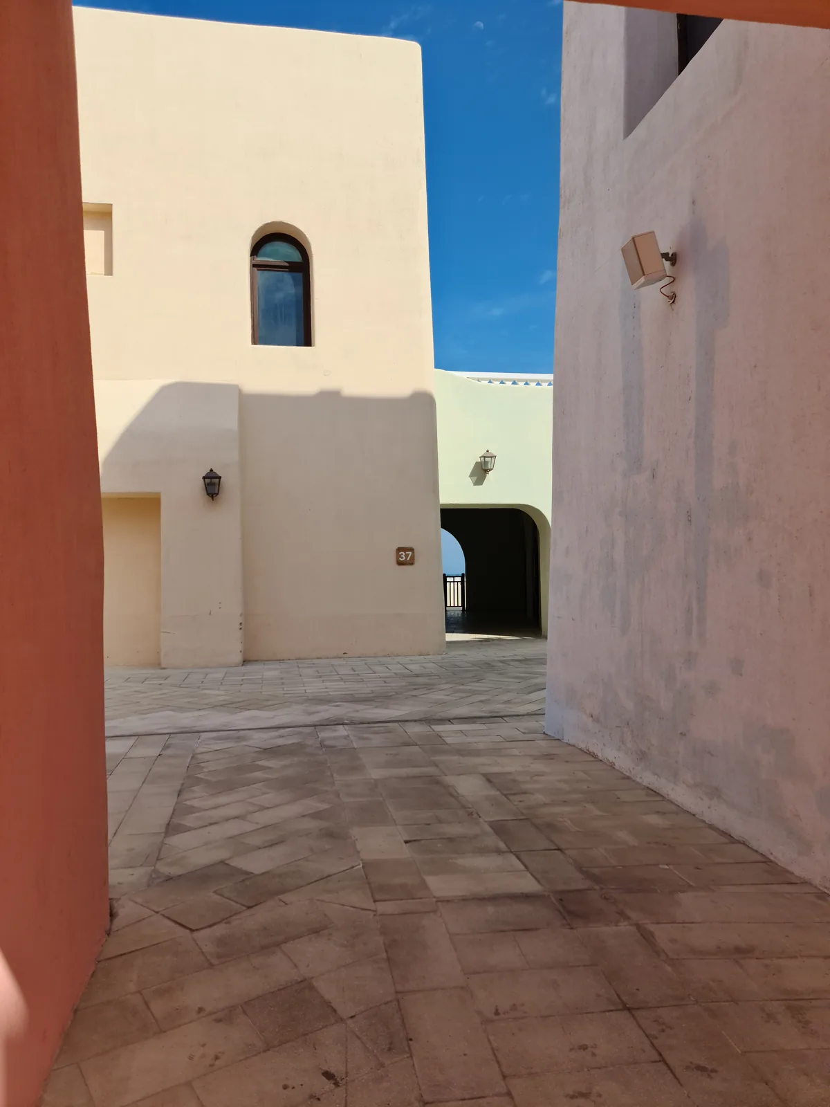 Narrow lane with white and cream pastel building facades in the Mina District, Doha