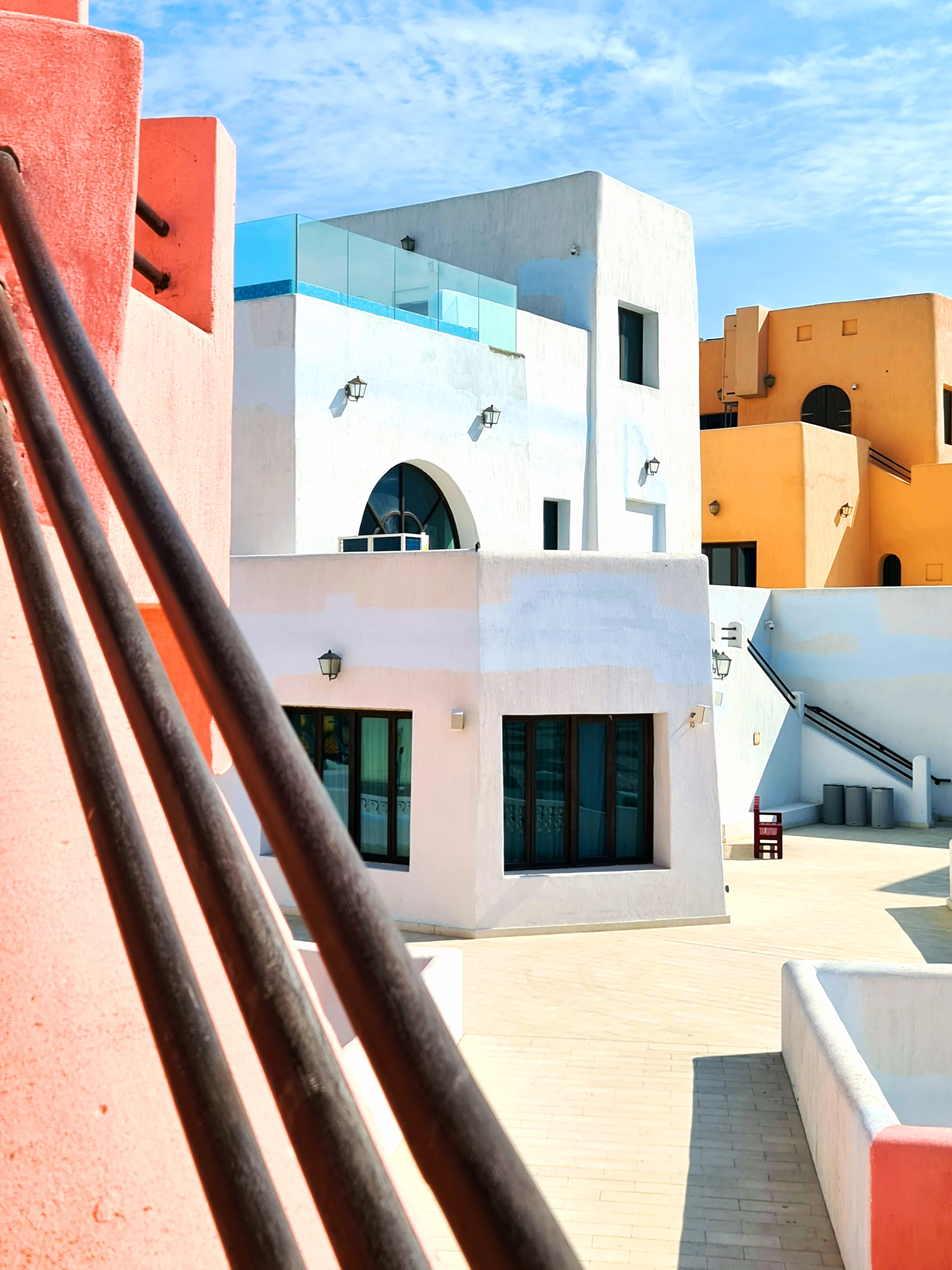 Terraced white and orange pastel buildings with outdoor stairs in the Mina District, Doha